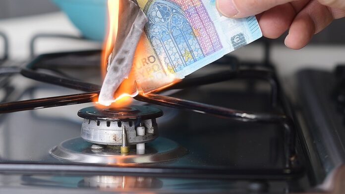 Gas price increase concept: 20 euro banknote burnt on a lit stov